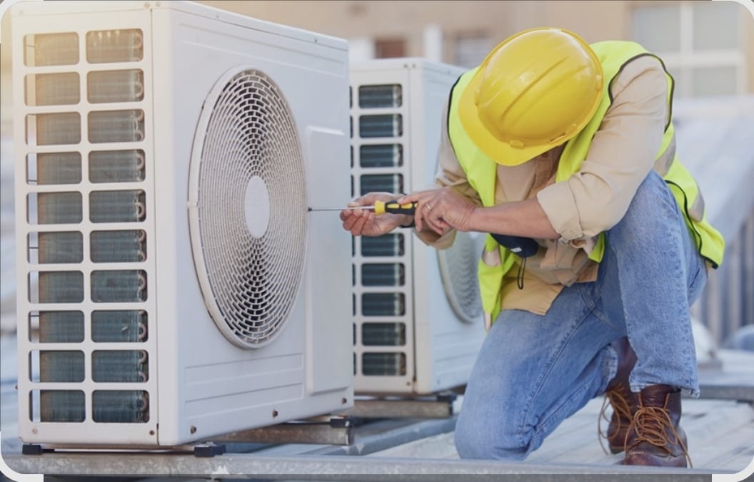 Technician servicing an outdoor air conditioning condenser unit